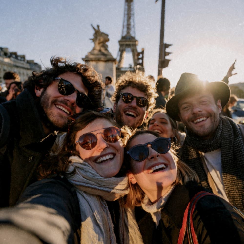 Friends piled into a selfie in front of the Eiffel Tower at golden hour