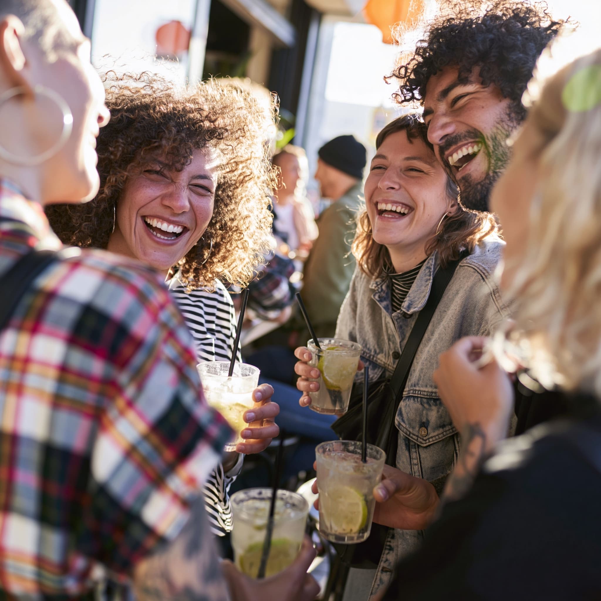 Friends laughing together over drinks at an outdoor bar